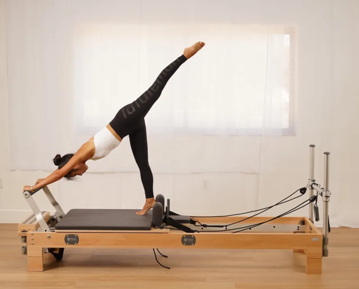 Femme réalisant un exercice sur un Reformer classique de studio en bois